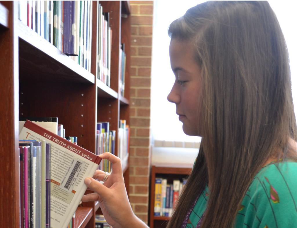 During+lunch+in+the+library%2C+senior+Allie+Parr+contemplates+what+book+she+wants+to+check+out.