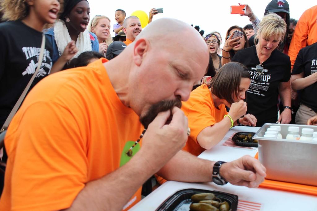 During the Jalapeño Eating Contest, Coach Damon Miller competes against Teacher Kimberly Helfenbein at Whataburger. 